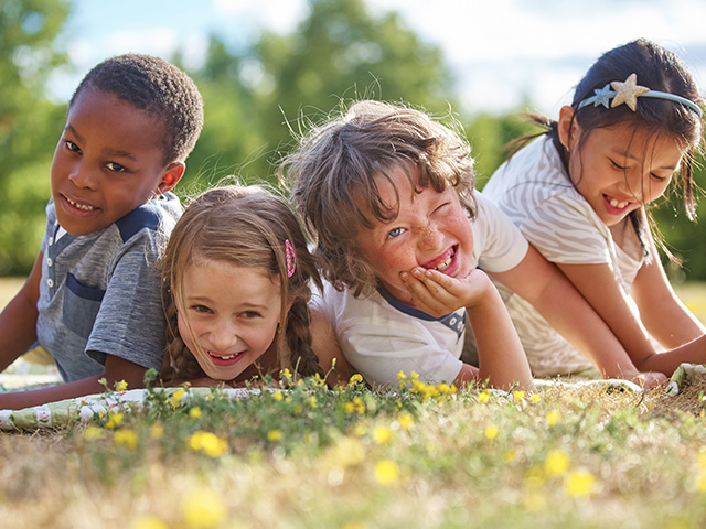 enfants s'amusant dans l'herbe pendant une colonie de vacances
