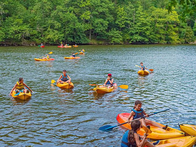 photographie de plusieurs kayaks sur une rivière ou un lac avec des enfants à bord
