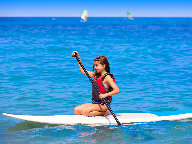 jeune fille sur un paddle sur le lac de garde lors d'un voyage itinérant pour adolescents