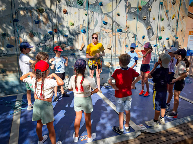 jeunes attentifs devant mur escalade artificiel explication monitrice