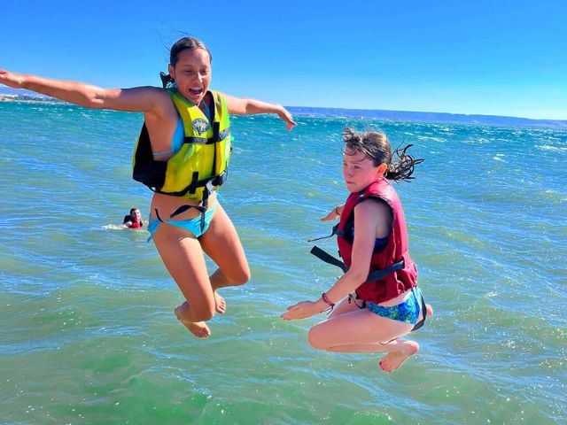 Jeunes filles qui sautent dans la mer et s'amusent en colonie de vacances cet été