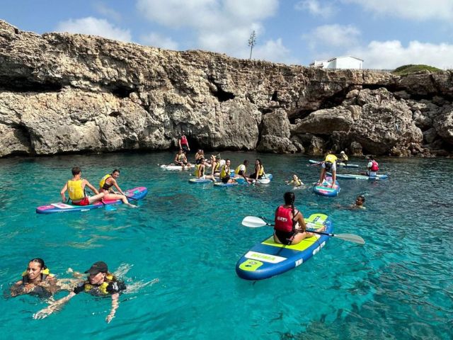 Groupe d'ados en colo de vacances à Minorque dans les Baleares qui font du paddle