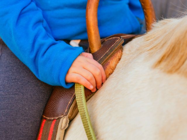 Jeune garçon qui monte à cheval en colo de vacances Equitation cet été