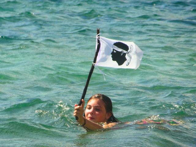 Jeune fille qui se baigne avec le drapeau corse en colo de vacances cet été