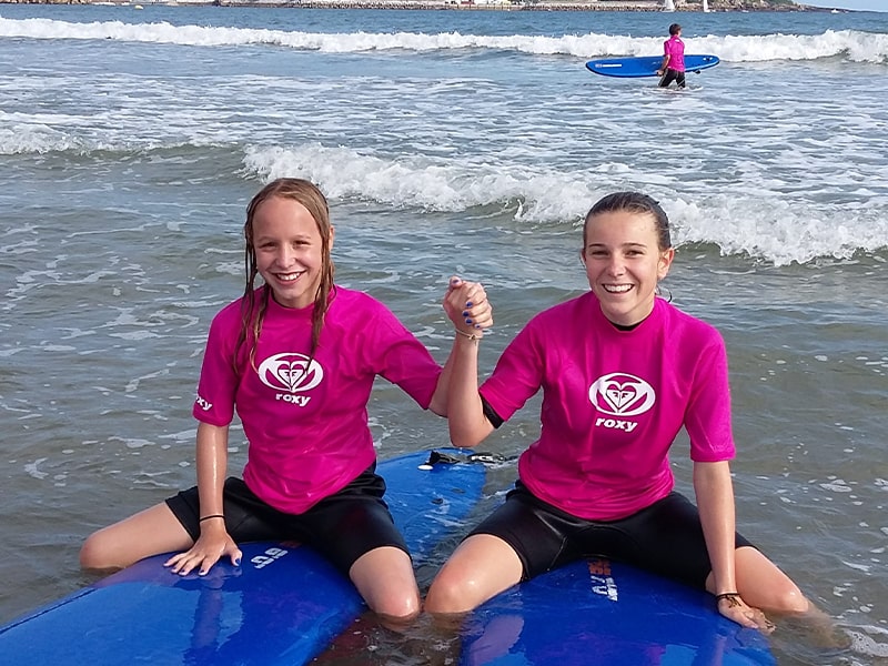 Deux jeunes filles avec le sourire qui profitent de leur colo de vacances surf à Anglet