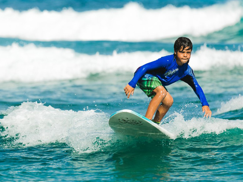 Jeune garçon qui surf les vagues d'Anglet lors de sa colo de vacances dans le Sud de la France