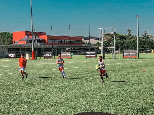 Jeunes qui courent sur le terrain de rugby lors de leur colo de vacances