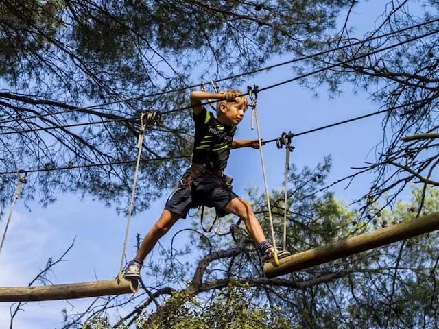 Enfant faidsant de l'accrobranche en colonie de vacances à la montagne