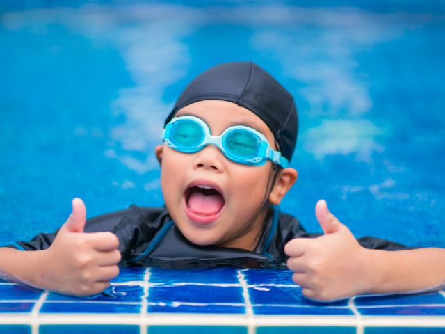 Jeune garcon qui apprend à nager en colo de vacances cet été