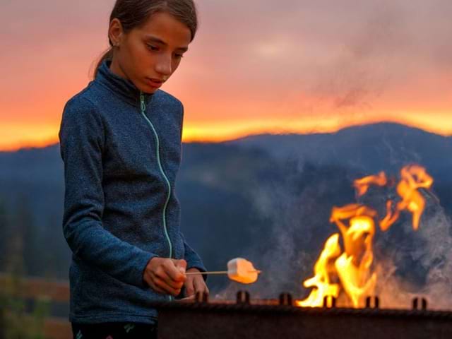 Jeune pré ado qui fait du feu en bivouac en colonie de vacances en itinérance à dos d'ane cet été