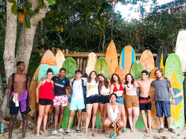 Groupe d'ados devant des planches de surf en colo de vacances au Brésil cet été