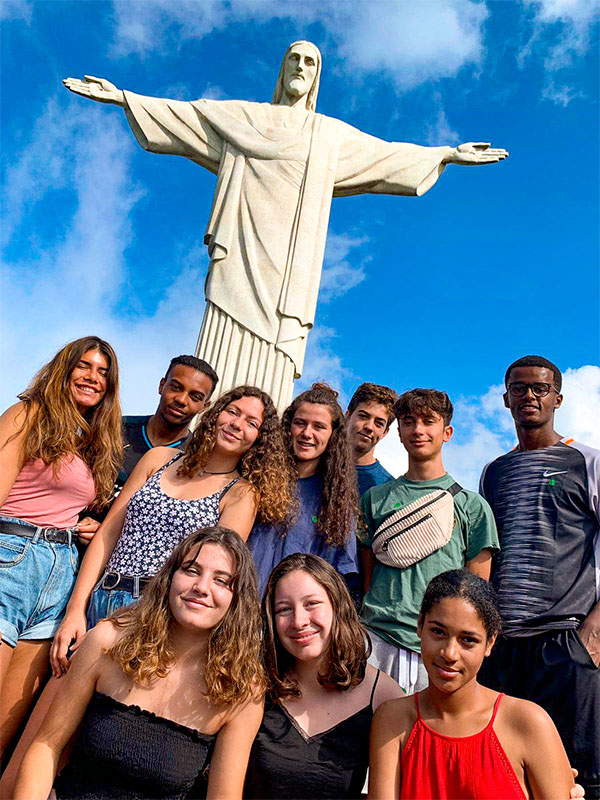 Groupe d'ados qui prend la pause devant la statue du Christ Rédempteur du haut du mont du Corcovado