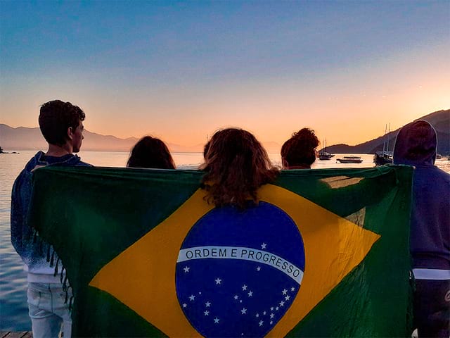 Groupe de jeunes qui prend la pose avec le drapeau du Brésil en colo de vacances au Brésil cet été 