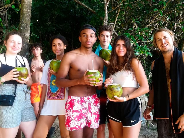 Groupe d'ados sirotant des noix de coco en colo de vacances au Brésil cet été