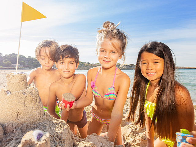 quatre enfants d'environ huit ans faisant des châteaux de sable sur la plage au bord de la mer cet été 