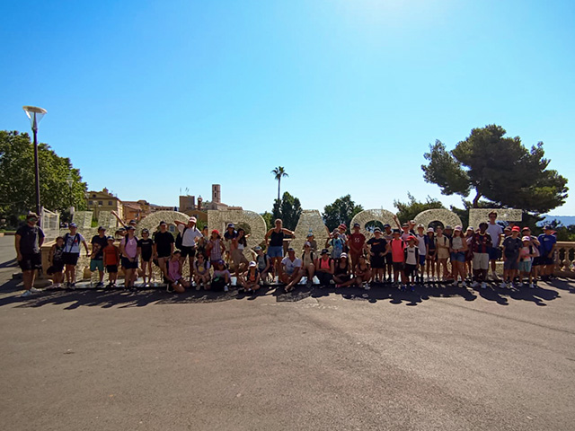 photo de groupe devant le nom de la ville de grasse visite d'une journée lors d'une colonie de vacances cet été