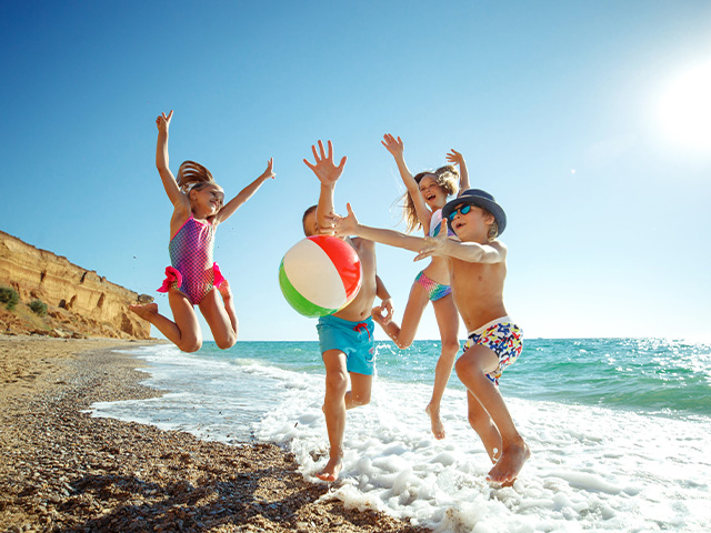jeunes enfants s'amusant avec un ballon sur la plage lors d'une colonie de vacances à Pégomas 