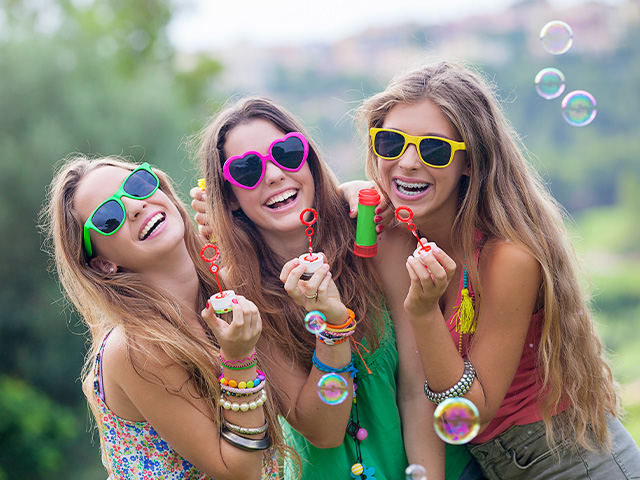 trois jeunes filles rigolant et s'amusant à faire des bulles en colo de vacances cet été