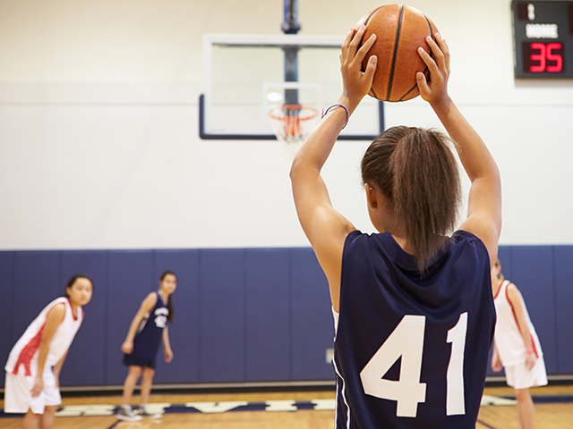 adolescente s'apprêtant à tirer et viser un panier de basket lors d'une colonie de vacances été