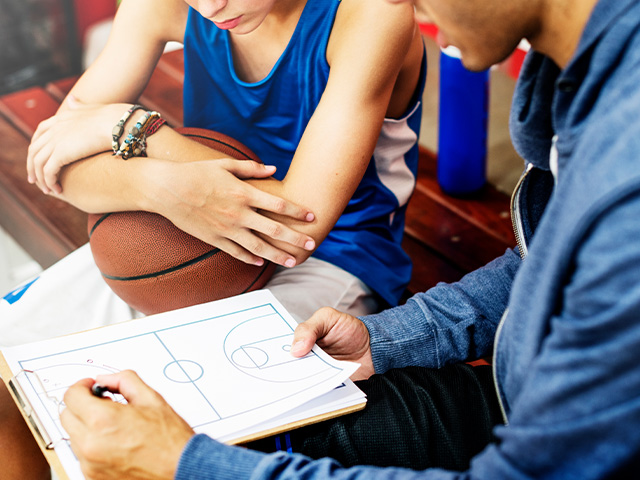 un coach expliquant à un jeune les placements nécessaires à adopter lors d'un match de basket