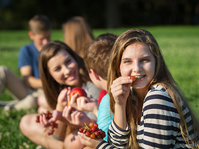 groupe d'adolescents assis sur l'herbe lors d'une colonie de vacances en plein air dans la Drôme