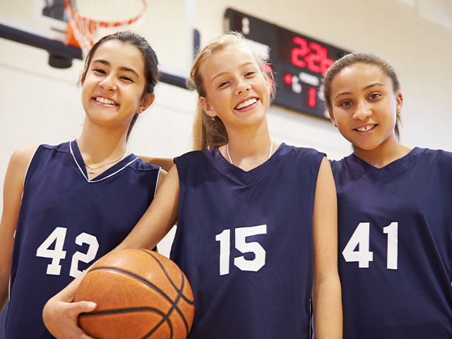 jeunes filles souriantes avec un ballon de basket à la main colo été