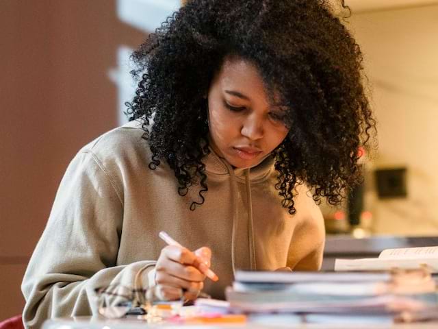 Jeune fille qui fait des exercices de maths en colo de vacances Soutien scolaire cet été