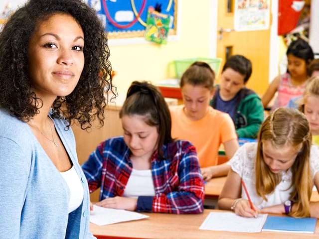 Groupe de soutien scolaire en colo avec une intervenante qui prend le temps d'expliquer avec les enfants