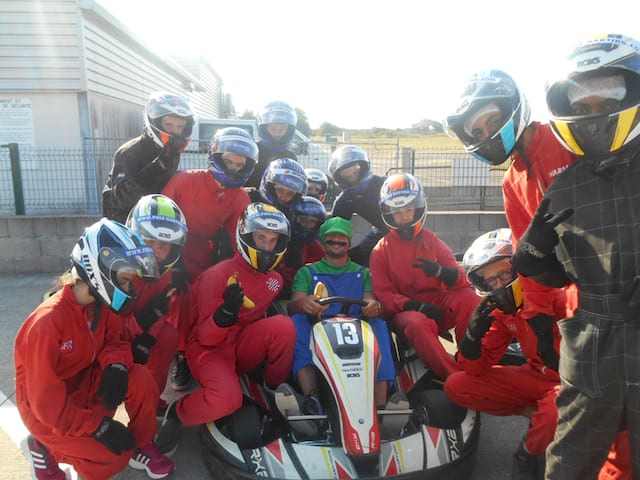 groupe d'enfants autour d'un kart apprenant la conduite en colonie de vacances