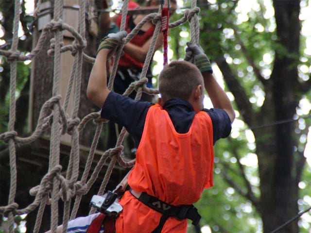 Enfant faisant de l'accrobranche en colonie de vacances à Définplanet