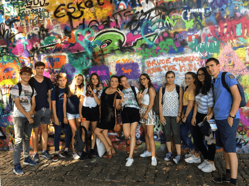Groupe de jeunes qui prend la pose devant un graffiti en colo de vacances en Europe cet été