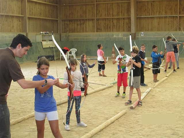 groupe d'enfants apprenant le tir à l'arc en colonie de vacances été