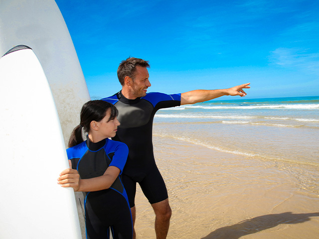 une jeune fille et un prof de surf sur la plage cet été
