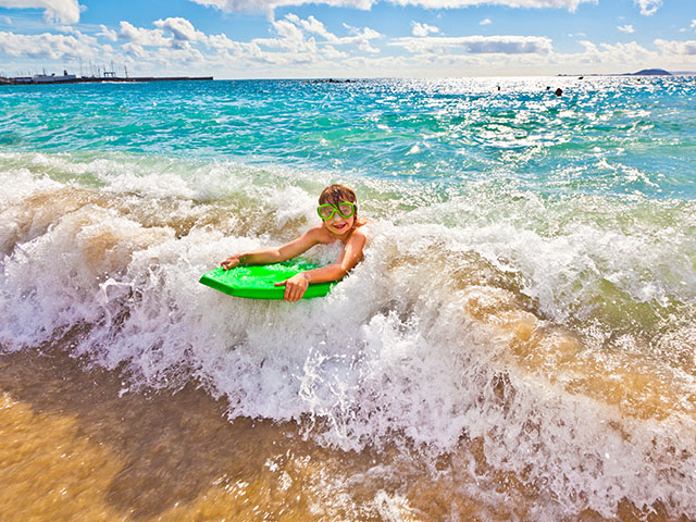 garçon et sa planche de surf dans l'eau lors d'une colo enfants cet été en vendée