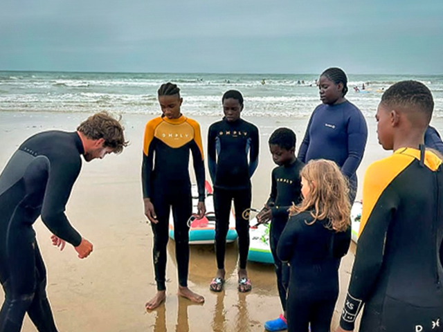 cours de surf avec explications du moniteur à un groupe de jeunes d'une dizaine d'années