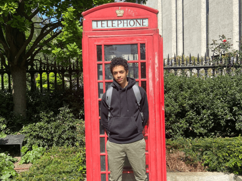 Jeune garçon qui prend la pose devant une cabine 100% British lors de sa colo de vacances à Londres cet été