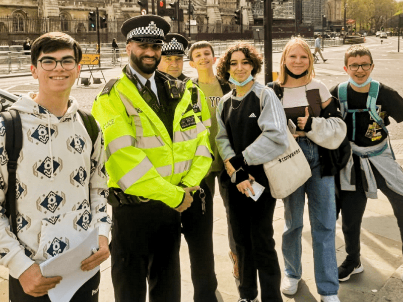 Groupe d'ados qui prend la pose avec un policier anglais durant leur colo de vacances cet été à Londres