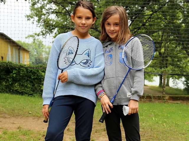 deux jeunes filles avec des raquettes de badminton en colonie de vacances cet été