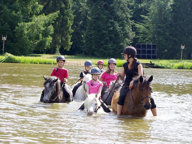 adolescents faisant de l'équitation dans le lac en colonie de vacances cet été