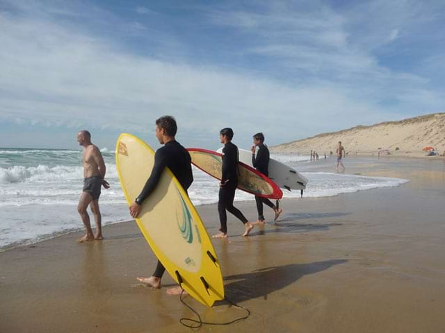 adolescents avec leur planche de surf au bord de l'eau en colonie de vacances d'été