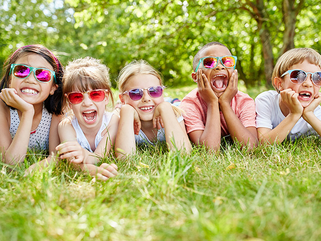 cinq enfants allongées sur l'herbe faisant des grimaces séjour été