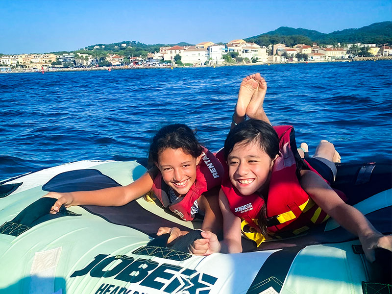 Jeunes filles qui rient sur une bouée tractable lors de leur colo de vacances de l'été