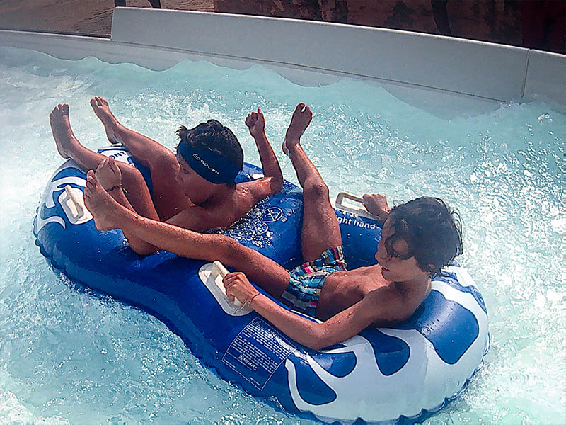 Jeunes qui s'amusent sur une bouée au parc d'attraction Aqualand lors de leur colo de vacances à la mer