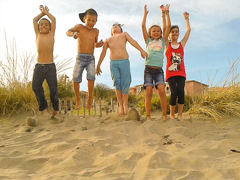 Jeunes enfants qui s'amusent dans le sable lors de leur colonie de vacances à la mer