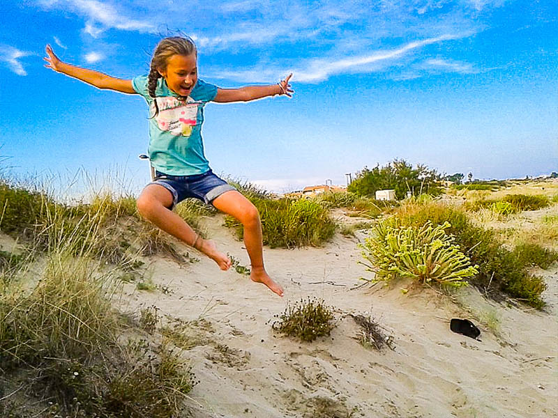 Jeune fille qui s'amuse dans le sable lors de sa colonie de vacances à la mer cet été