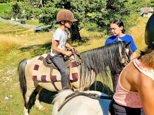 Jeune garçon qui profite de sa colo de vacances Poney en pleine nature cet été