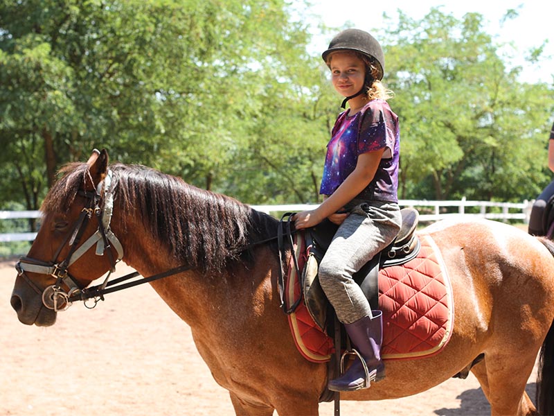 Jeune fille faisant de l'équitation en colonie de vacances cet été