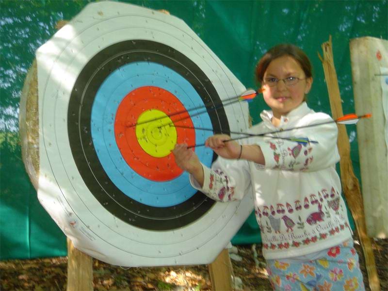 jeune fille enlevant les fèches de la cible de tir à l'arc en colonie de vacances cet été