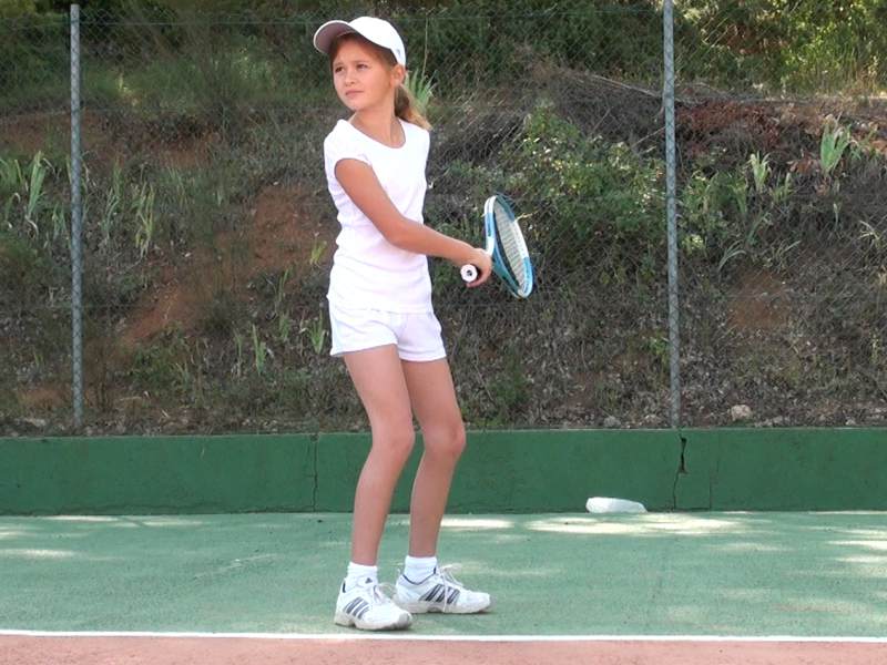 Fillette de 8 ans jouant au tennis en colonie de vacances d'été multiactivités