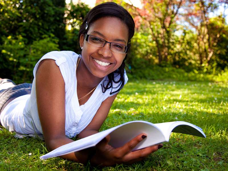 Jeune fille souriante lisant un livre